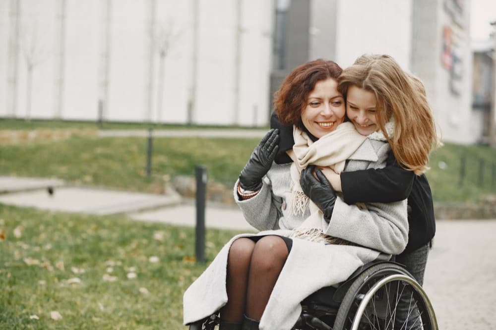 Deux femmes partageant un moment de complicité, dont une personne en fauteuil roulant